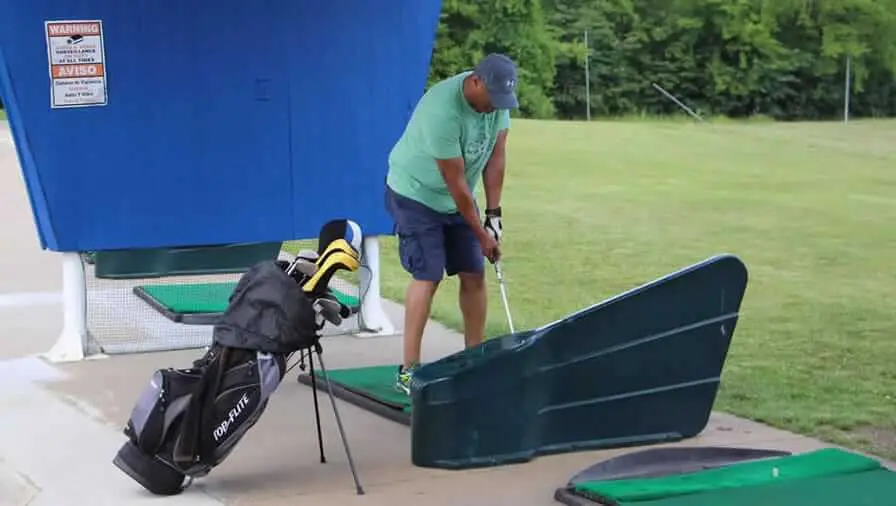 Golfer getting ready to swing on a driving range tee mat